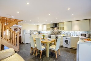 Une cuisine moderne avec un coin repas, un lave-linge et un escalier.