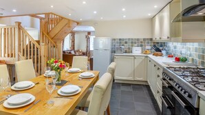 Une cuisine moderne avec un coin repas, un escalier en bois et une vue sur le salon.