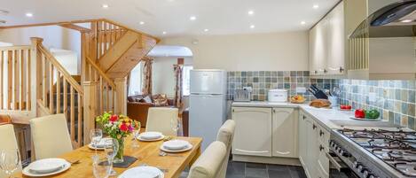 Eine moderne Küche mit Essbereich, einer Holztreppe und Blick zum Wohnzimmer.