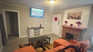 Un salon comprenant un canapé, une table basse, une cheminée et un téléviseur fixé au mur.