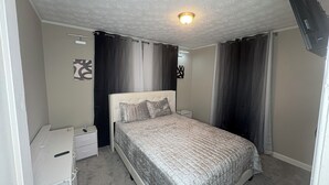 Une chambre à coucher avec un lit, une table de chevet, un bureau et un luminaire au plafond.