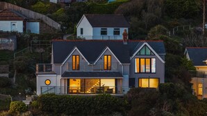 A two-story house with a balcony, large windows, and a visible outdoor seating area. - 5 Bed in Mortehoe (oc-c30855) (Mortehoe)