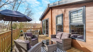 A wooden deck with wicker furniture and a large umbrella. - 2 Bed in Warton (oc-s31031) (Warton)