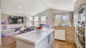 A modern kitchen with a central island, built-in appliances, and a large window. - 2 Bed in Warton (oc-s31031) (Warton)