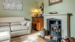A living room with a beige sofa, a fireplace, a lamp, and a painting on the wall.
