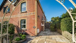 A brick house with a garden entrance, a mailbox, and a gate.