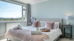 A bedroom with a large bed, a view of the outdoors, a bedside table with a lamp, and a window with curtains. - 3 Bed in St. Helens (oc-y30961) (Saint Helens)