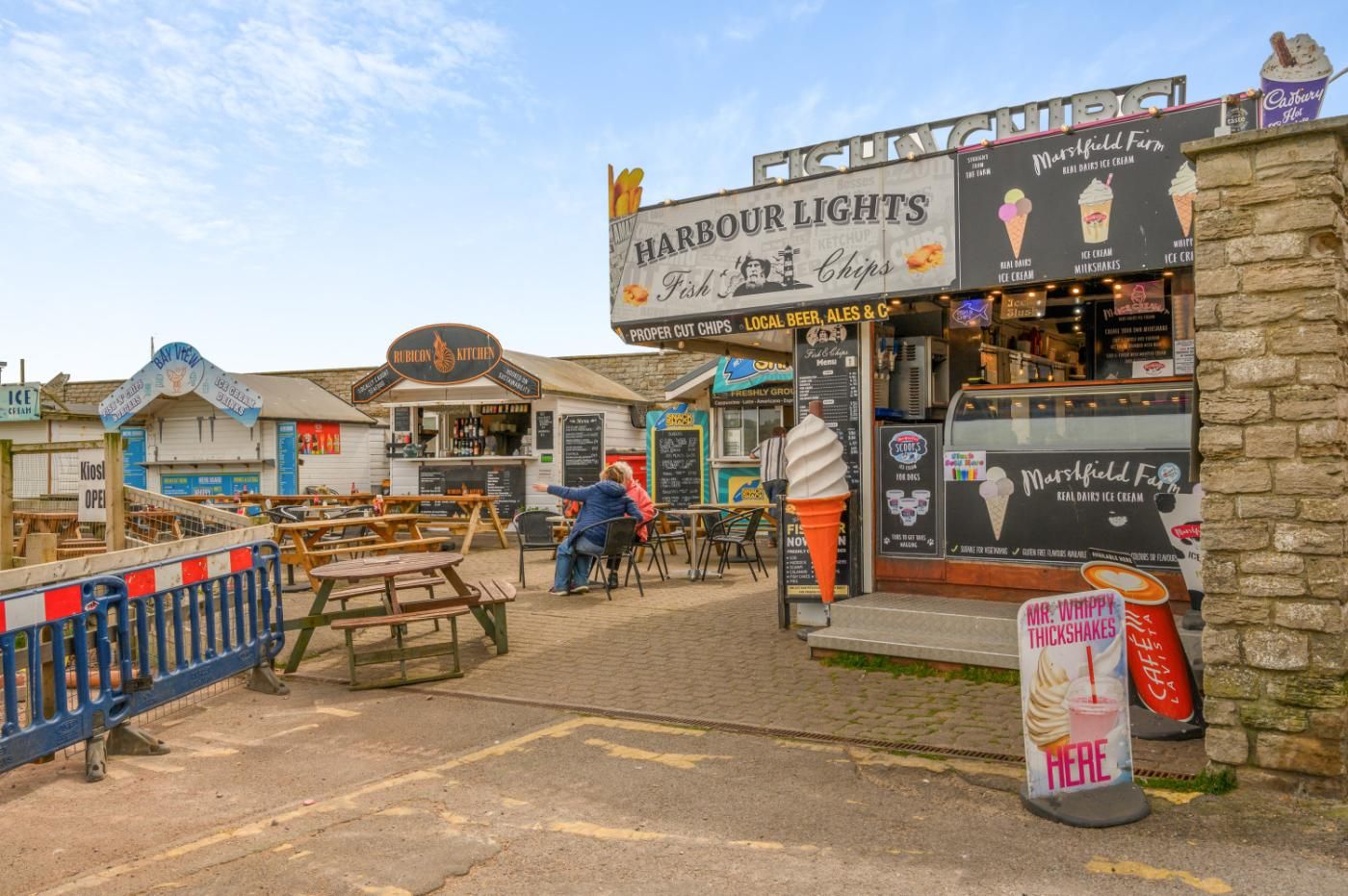 A seaside food stall with a sign for Harbour Lights, offering fish & chips and ice cream.