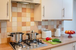 A kitchen with two stainless steel pots on a gas stove, a white toaster, and a fruit bowl on the counter. - 3 Bed in Weymouth (oc-a30944) (Weymouth)