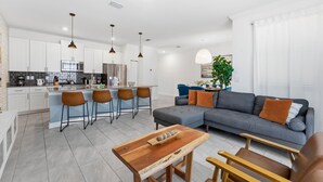 Een moderne keuken met witte kasten, een centraal kookeiland met barkrukken en hanglampen.