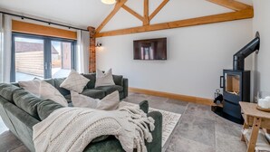 Ein gemütliches Wohnzimmer mit einer Couch, Kissen, einer Decke, einem Kamin und einem Fernseher.
