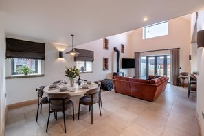 Un vaste espace de vie comprenant une table à manger pour quatre personnes, un canapé et un téléviseur fixé au mur.