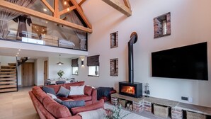 Un'ampia zona giorno con soffitto alto, camino, televisore a schermo piatto e zona pranzo.