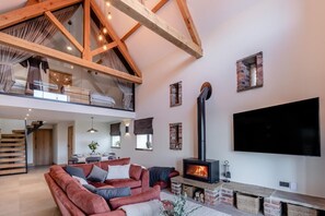 Un vaste espace de vie doté d’un haut plafond, d’une cheminée, d’un téléviseur à écran plat et d’un coin repas.
