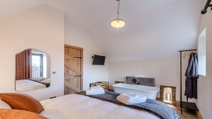 Camera da letto moderna con un letto, uno specchio grande, una TV, una vasca da bagno e un armadio.