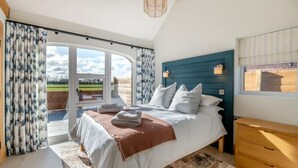 A bedroom with a bed, a wooden dresser, a window with curtains, and a view of the outdoors. - 2 Bed in Beeford (oc-t90892) (Beeford)