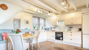 Een moderne keuken met witte kasten, een houten eettafel en een inbouwoven.