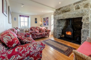 A cozy living room with a stone fireplace, patterned sofas, and a rug.