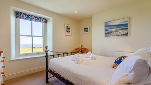 Une chambre à coucher avec un lit, une fenêtre donnant sur un beau paysage et un tableau accroché au mur.