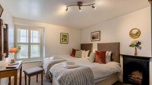 A hotel room with two beds, a desk with a lamp, a fireplace, and artwork on the walls. - 2 Bed in Field Broughton (oc-l31021) (Field Broughton)