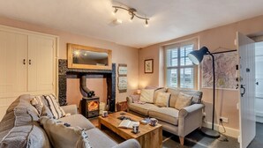 A cozy living room with a fireplace, two sofas, a coffee table, and a map on the wall. - 2 Bed in Field Broughton (oc-l31021) (Field Broughton)