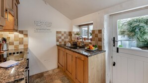 A kitchen with a tiled backsplash, wooden cabinets, a granite countertop, and a window with a view of a garden. - 2 Bed in Field Broughton (oc-l31021) (Field Broughton)