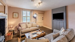 A living room with a sofa, a coffee table, a TV, and a door. - 2 Bed in Field Broughton (oc-l31021) (Field Broughton)