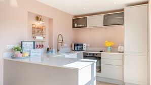 Una cocina moderna con una isla central, armarios blancos y un horno integrado.