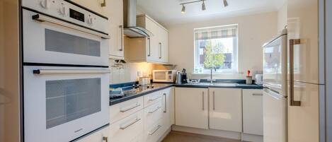 Een microgolfoven, een oven, een vaatwasser, kookgerei, borden en bestek