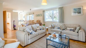A spacious living room with two sofas, a coffee table, and a dining area with chairs and a table. - 3 Bed in Brancaster (oc-r30695) (Brancaster)