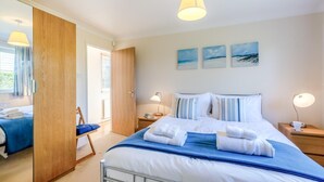 A well-lit bedroom with a bed, bedside tables, a chair, and artwork on the wall. - 3 Bed in Brancaster (oc-r30695) (Brancaster)