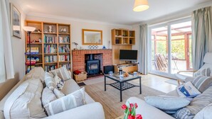 A cozy living room with a fireplace, a sofa set, a bookshelf, and a TV. - 3 Bed in Brancaster (oc-r30695) (Brancaster)
