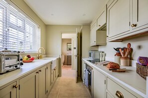 A narrow kitchen with a toaster, a bowl of fruit, and a microwave. - 2 Bed in Burton Bradstock (oc-h30904) (Burton Bradstock)