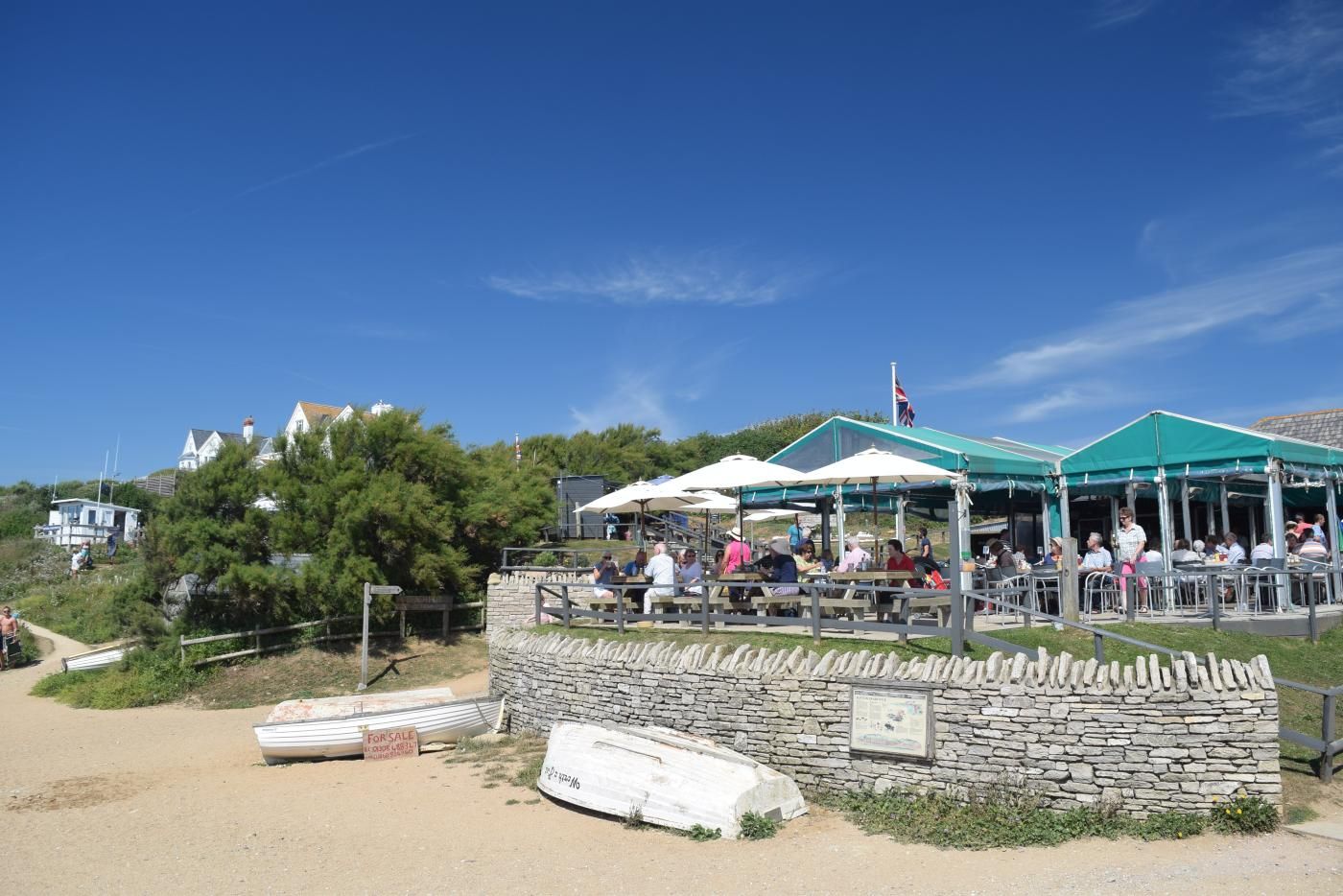 Une zone côtière dotée d’un mur de pierre, d’un espace de repos abrité avec des parasols et d’un drapeau.