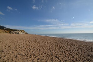 Ein sandiger Strand mit blauem Himmel und ruhigem Meer.