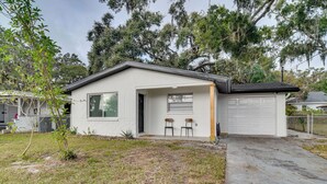 Een gelijkvloers huis met een garage, een klein terras met twee stoelen, en een verzorgd gazon.