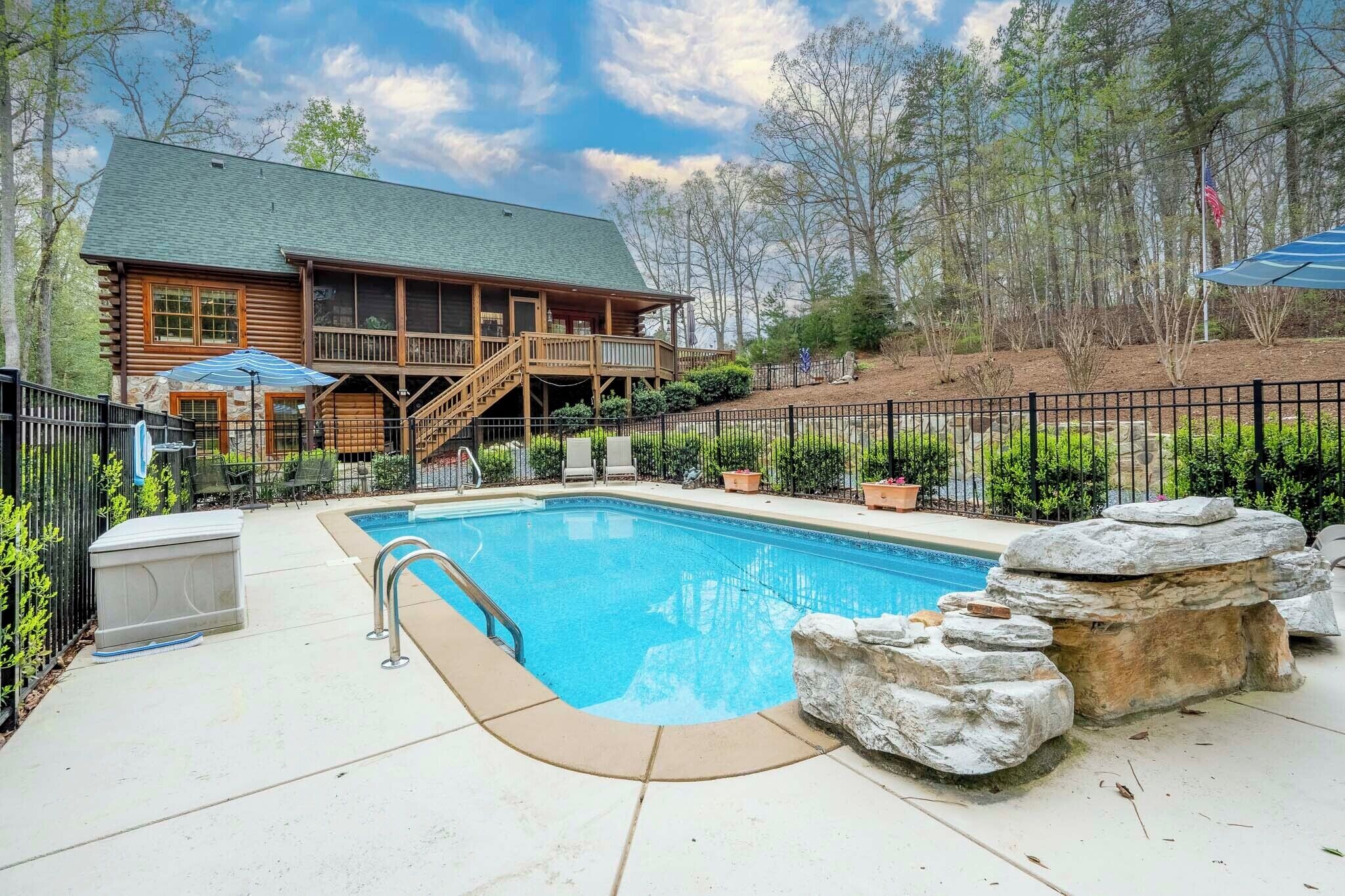 A log cabin with a swimming pool, outdoor seating, and a deck.