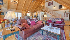 A spacious living room with a high wooden ceiling, leather sofas, a coffee table, and a staircase leading to an upper level. - 1 Mi to Lake Tillery: Outdoor Retreat w/ Hot Tub! (Mt Gilead)
