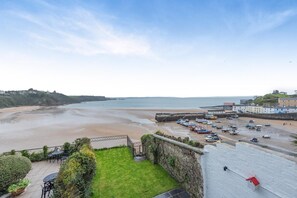 A coastal view with a sandy beach, a pier, and a row of boats. - 7 Bed in Tenby (oc-b30996) (Tenby)