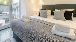 Ein Hotelzimmer mit einem großen Bett, Blick durch eine Schiebetür und einem kleinen Balkon.