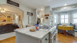 Een moderne keuken met een centraal eiland, inbouwapparatuur en een zithoek met een bank.