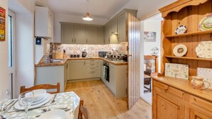 A compact kitchen with a dining area, wooden cabinets, a microwave, and a small dining table set for four.