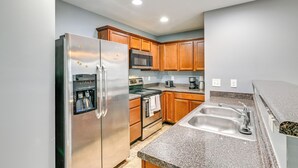 A modern kitchen with stainless steel appliances, wooden cabinets, granite countertops, and a double sink. - 4BR Pet-Friendly Charlotte Home | 6 Mi to CLT (Charlotte)
