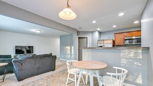 A modern living room with a grey sofa, a TV, and a dining area with a round table and white chairs. - 4BR Pet-Friendly Charlotte Home | 6 Mi to CLT (Charlotte)