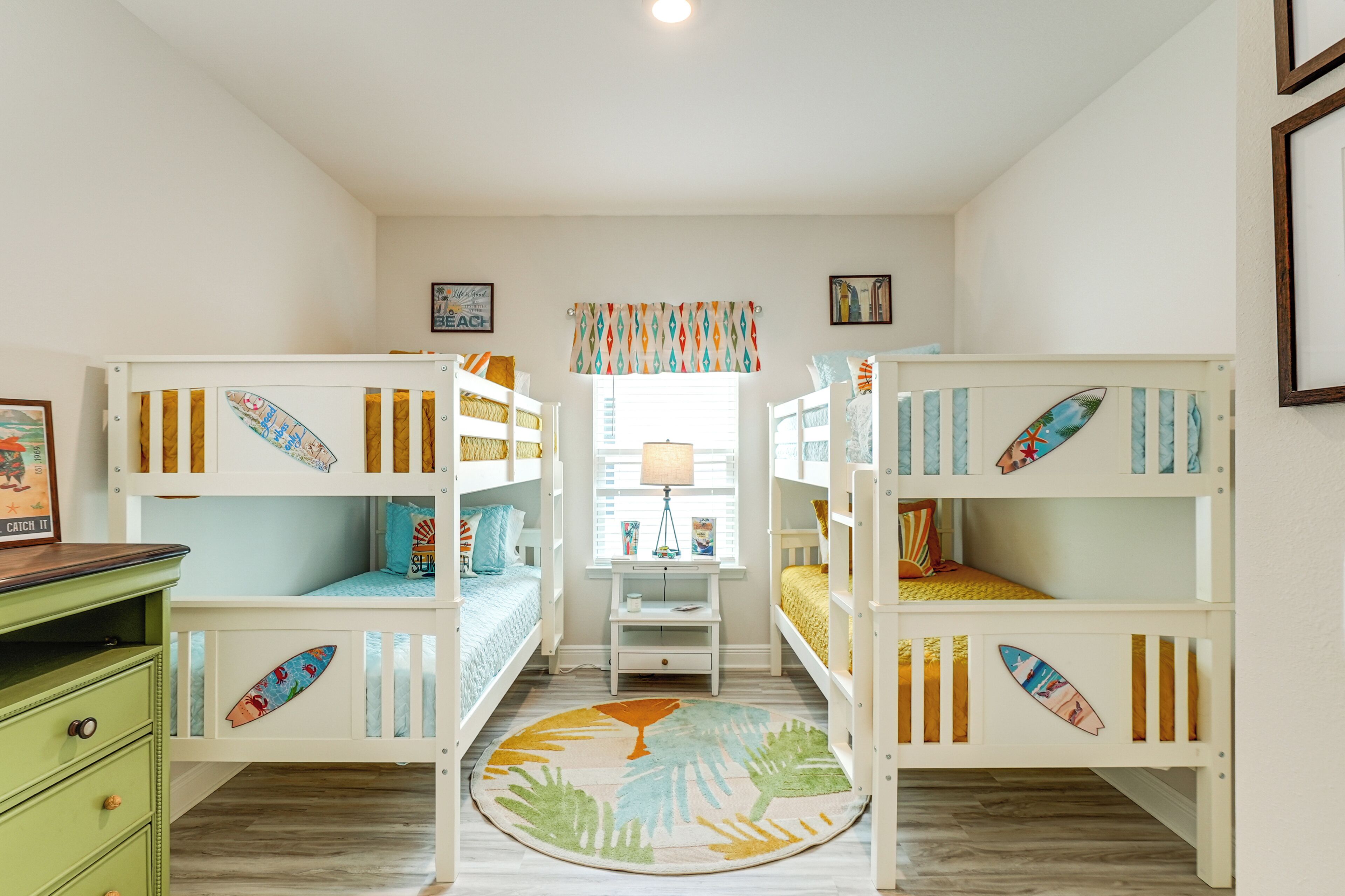 A children's room with bunk beds, a small desk, and a window with a view.