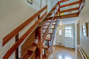 Un escalier en bois, doté d’une rampe, mène à une porte avec une fenêtre.