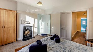 A bedroom with a bed, a fireplace, a wardrobe, and a bathroom visible through an open door. - 1 Bed in Whitby (oc-l31011) (Whitby)