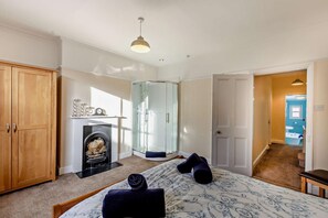 Ein Schlafzimmer mit Bett, Kamin, Kleiderschrank und einem durchgegangenen Tür angedeuteten Badezimmer.