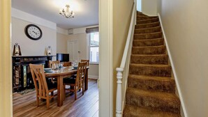 A staircase with carpeted steps and a white handrail, leading to a dining area with wooden chairs and a table set for four. - 1 Bed in Whitby (oc-l31011) (Whitby)