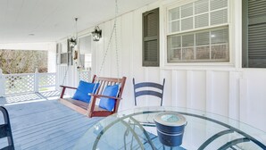 A covered porch with a glass table, a wooden swing, and a white fence. - Secluded Getaway on 40 Acres in Lawrenceburg! (Lawrenceburg)
